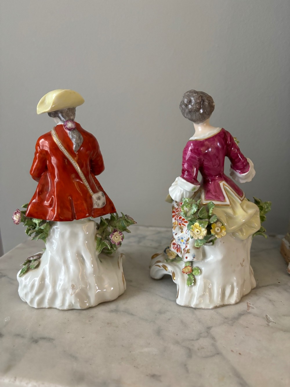 A pair of 19th-century Edme Samson hard-paste porcelain figurines depicting an 18th-century courtly man and woman in colourful enamelled attire seated on gilded rococo scroll bases. View IV