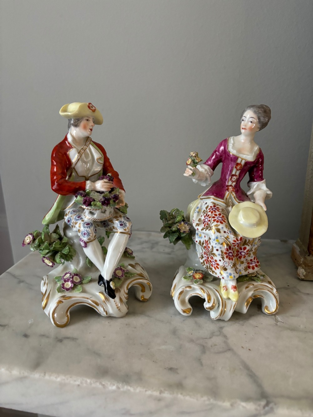 A pair of 19th-century Edme Samson hard-paste porcelain figurines depicting an 18th-century courtly man and woman in colourful enamelled attire seated on gilded rococo scroll bases. View V