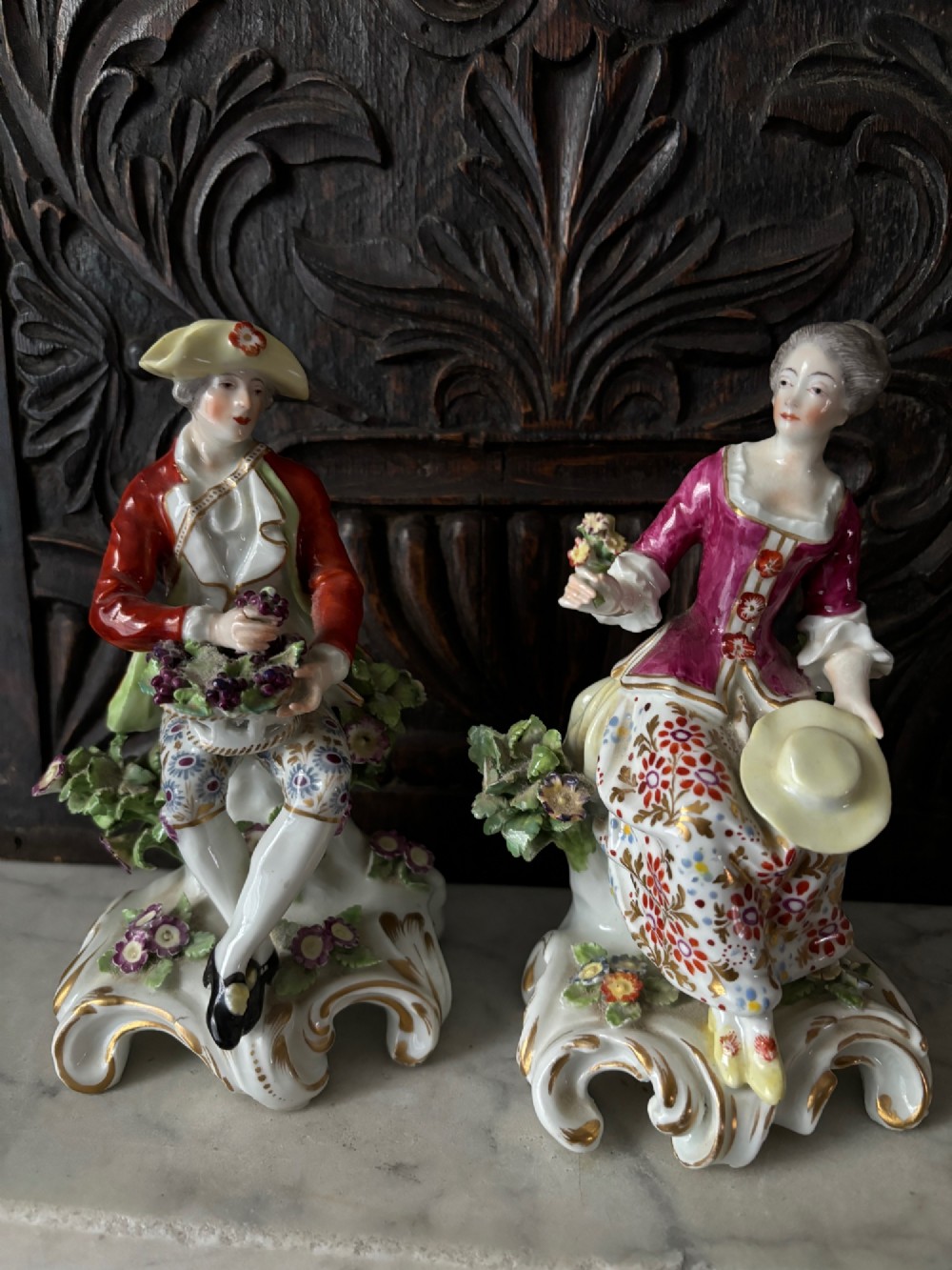 A pair of 19th-century Edme Samson hard-paste porcelain figurines depicting an 18th-century courtly man and woman in colourful enamelled attire seated on gilded rococo scroll bases. View IX