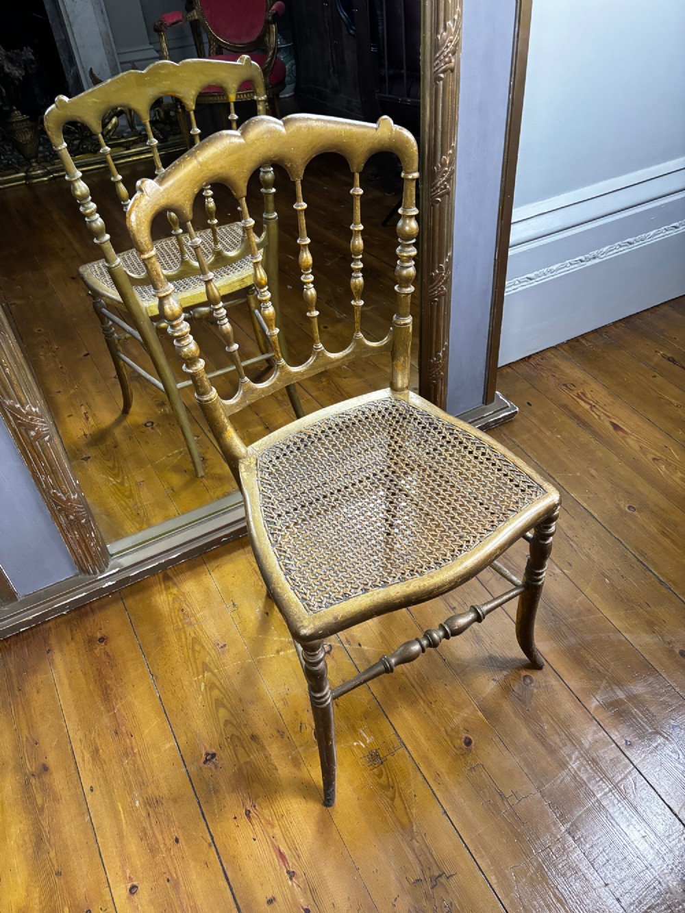 A 19th-century French giltwood salon chair featuring turned spindles, a woven cane seat, and slender curved legs with a distressed gold finish. View IV