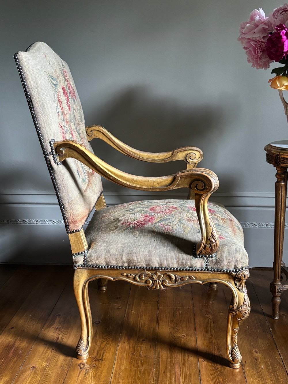 A late 19th-century French Regence style giltwood open armchair featuring carved scrollwork arms, cabriole legs, and floral tapestry upholstery. View VIII