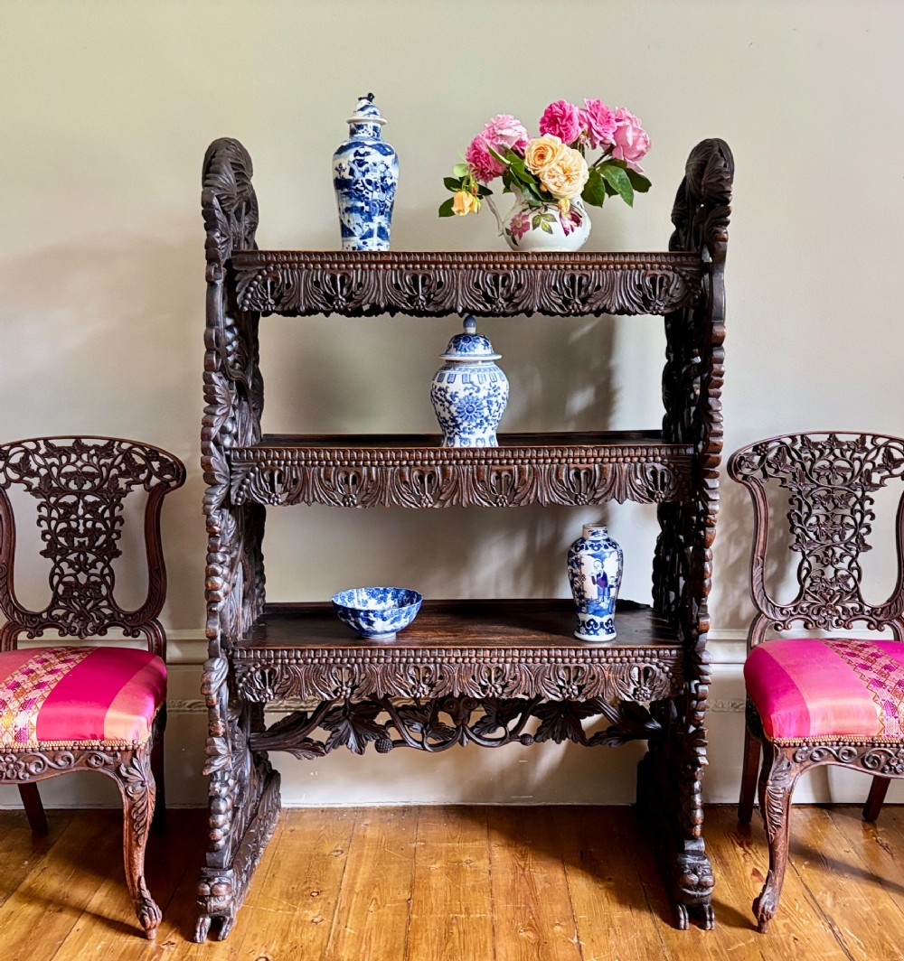 A 19th-century three-tiered Anglo-Indian padauk shelving unit featuring deeply carved floral friezes, openwork side panels, and sculpted feet. View II