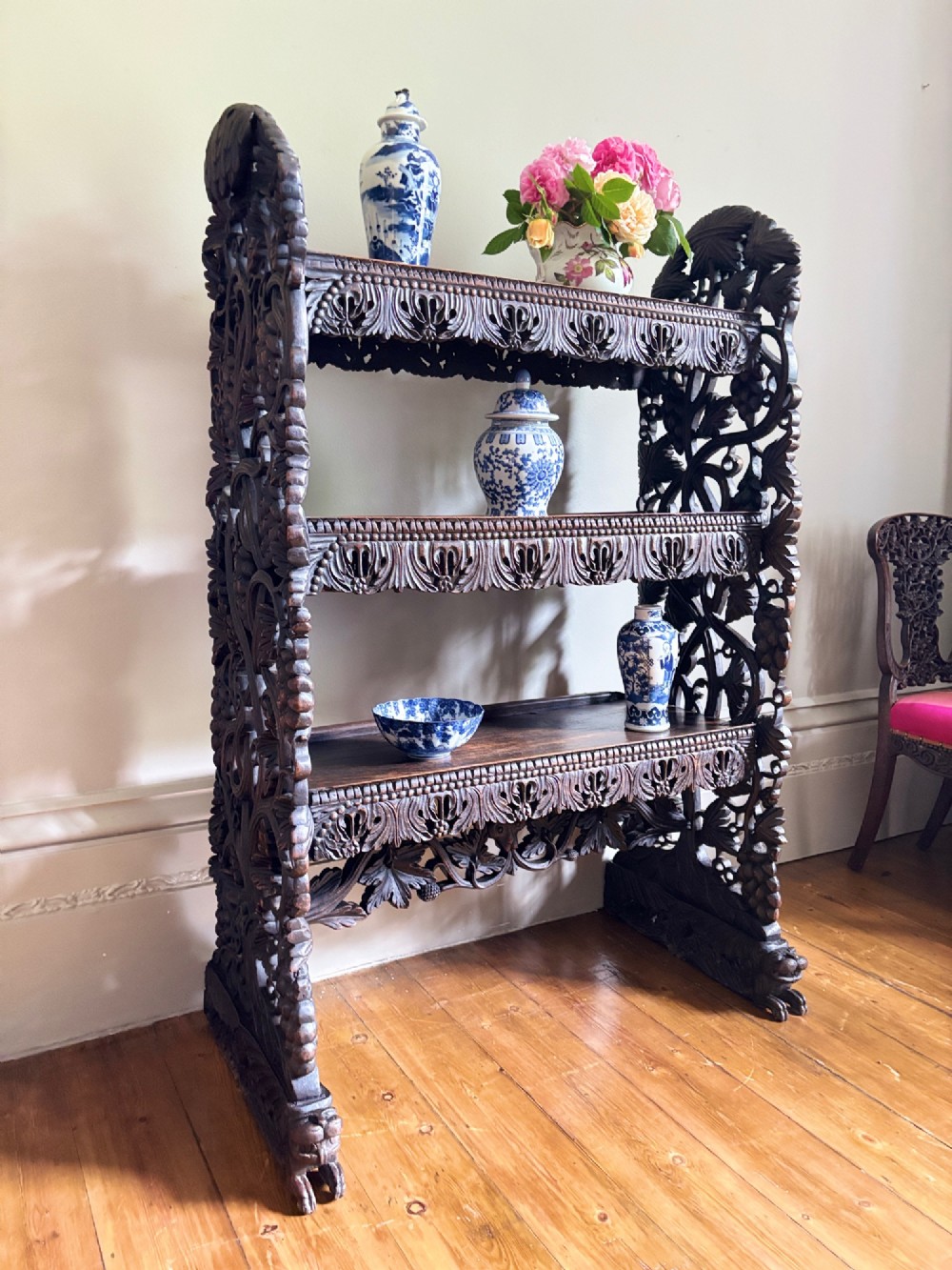 A 19th-century three-tiered Anglo-Indian padauk shelving unit featuring deeply carved floral friezes, openwork side panels, and sculpted feet. View VIII