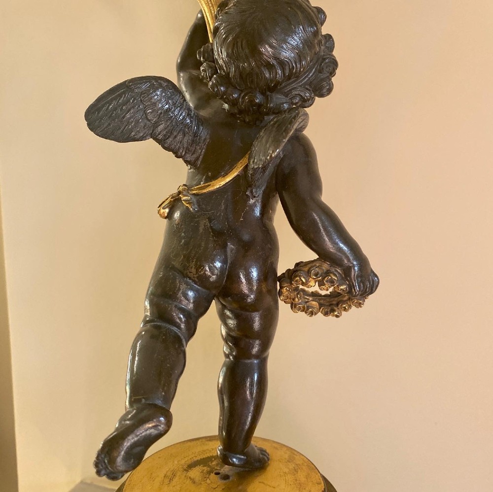 A pair of patinated bronze putti figures standing on marble pedestals, each holding gilt bronze scrollwork candelabra arms. View XIV