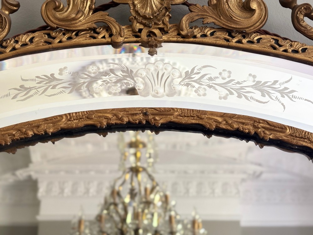 A late 19th-century French Rococo style wall mirror featuring an ornate gilt bronze frame, a central cherub cresting, and etched glass border panels. View VI