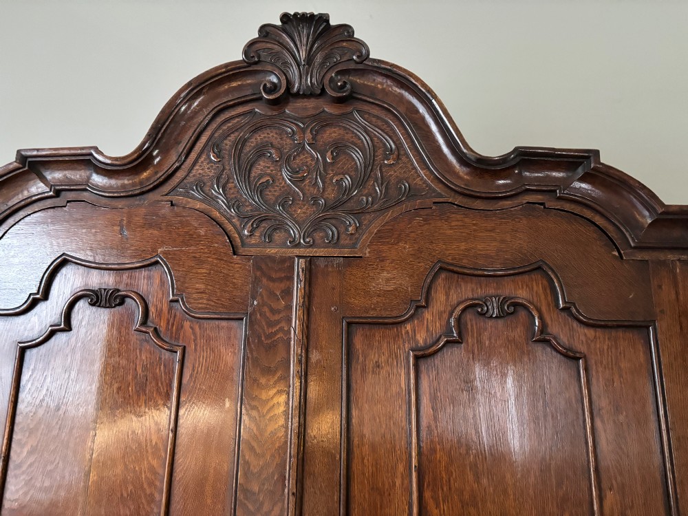 An eighteenth-century carved oak Dutch linen press featuring shaped double doors above a three-drawer base with brass handles and claw feet. View III