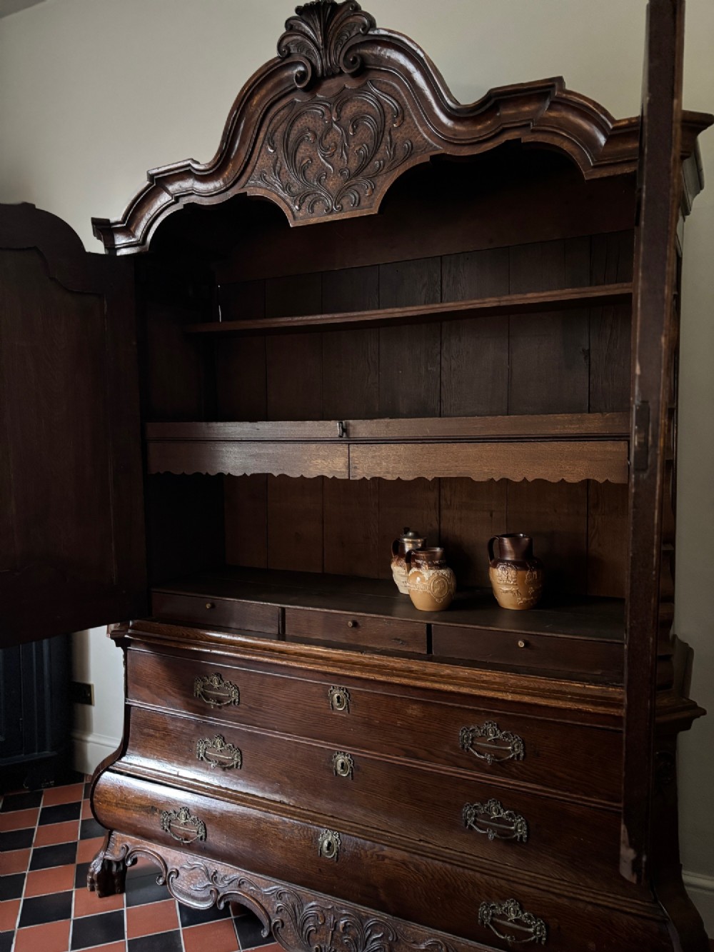 An eighteenth-century carved oak Dutch linen press featuring shaped double doors above a three-drawer base with brass handles and claw feet. View VIII