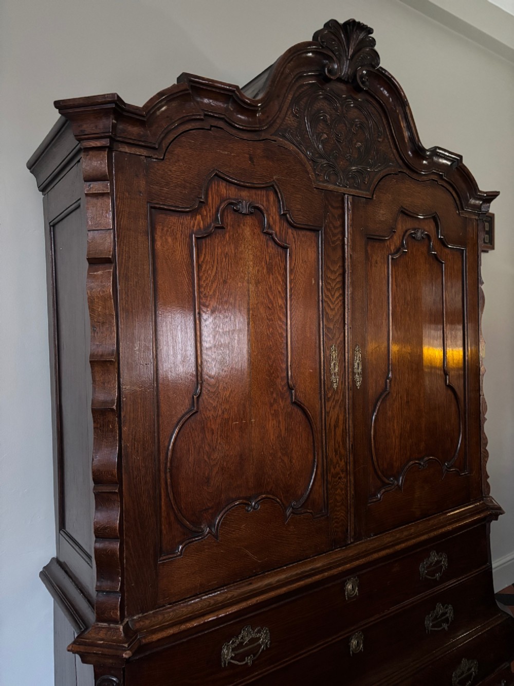 An eighteenth-century carved oak Dutch linen press featuring shaped double doors above a three-drawer base with brass handles and claw feet. View XII