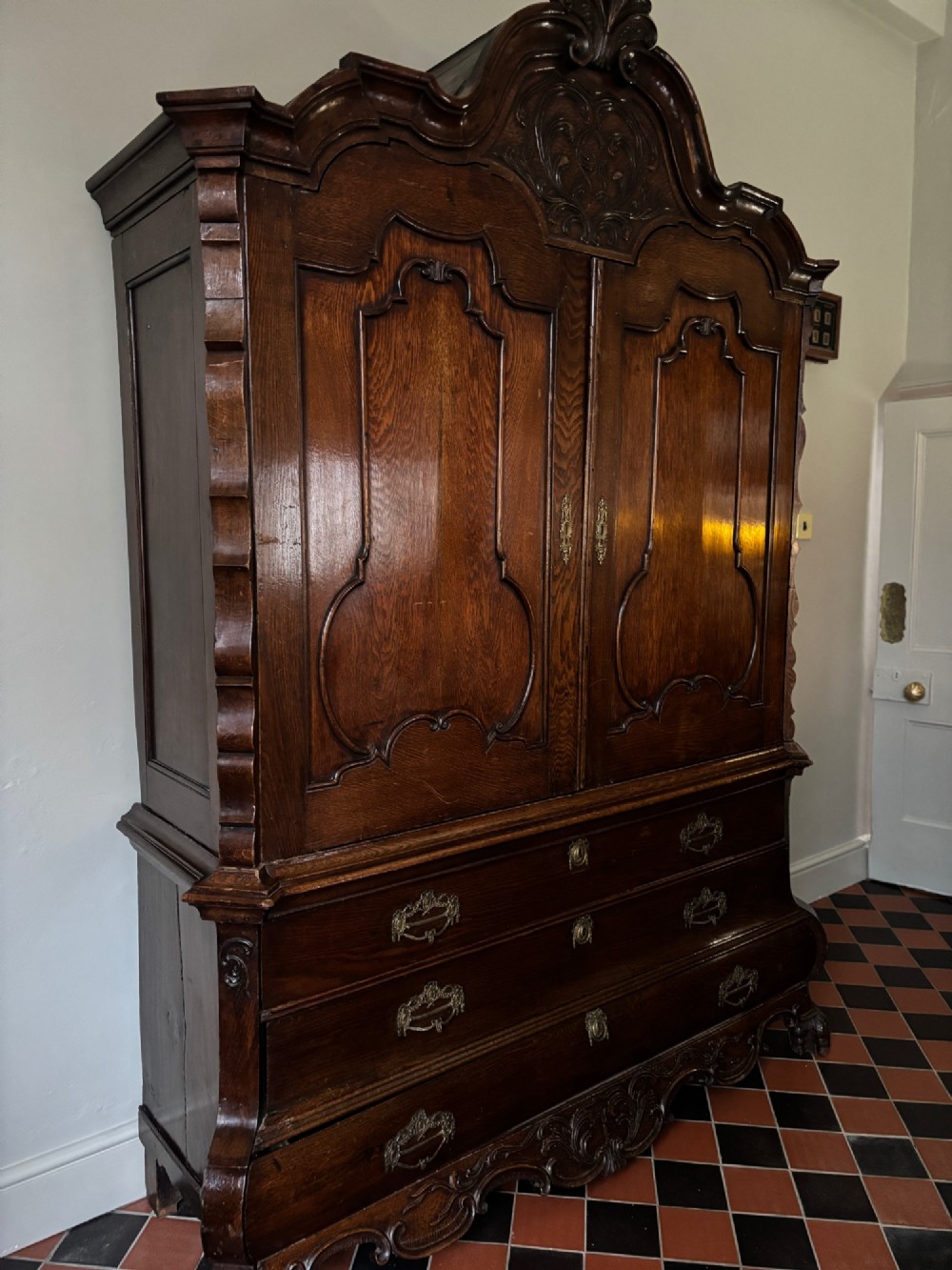 An eighteenth-century carved oak Dutch linen press featuring shaped double doors above a three-drawer base with brass handles and claw feet. View XIII