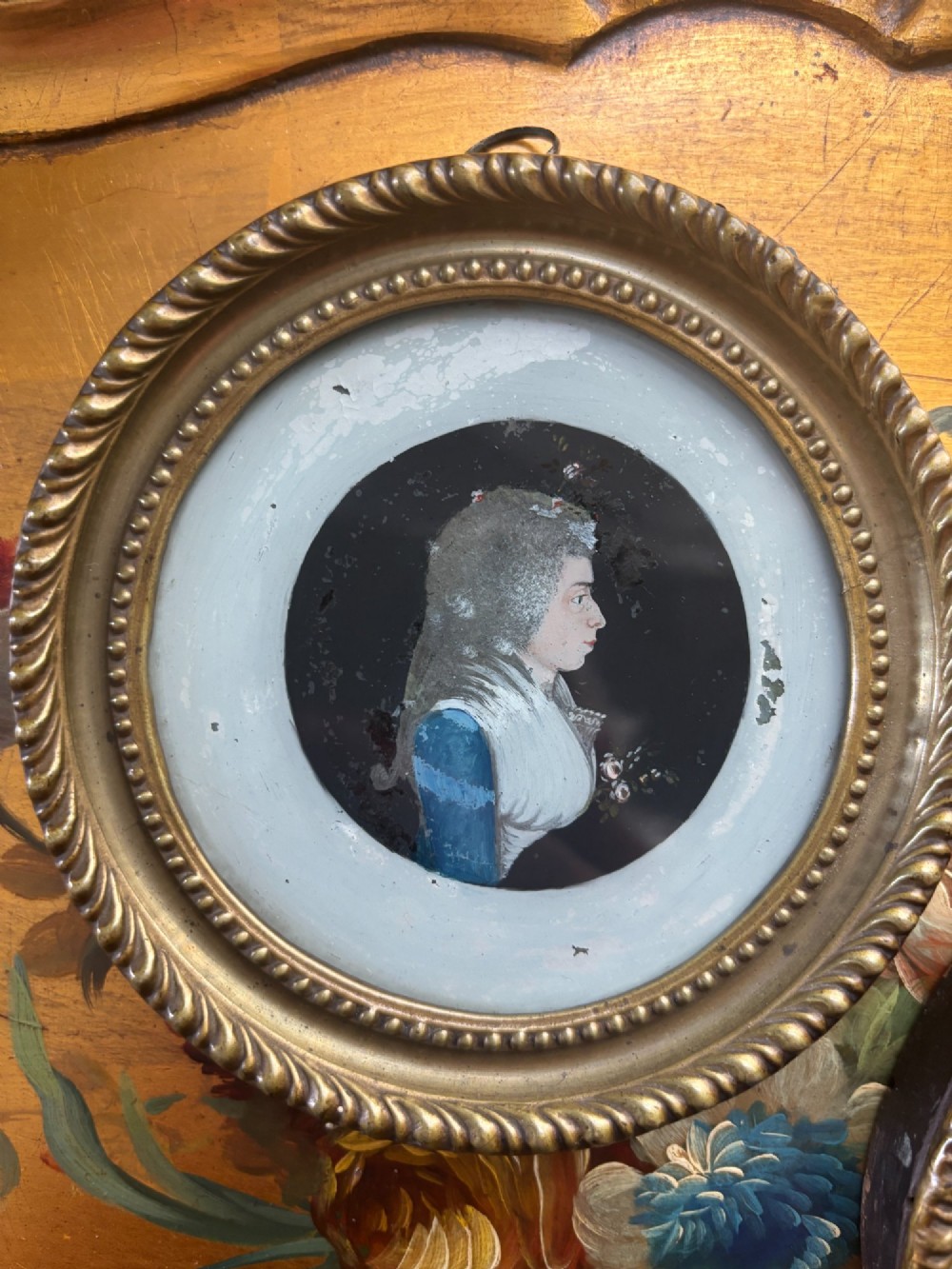 A pair of circular Georgian reverse painted glass miniature profile portraits depicting a lady and gentleman in gilt frames. View II