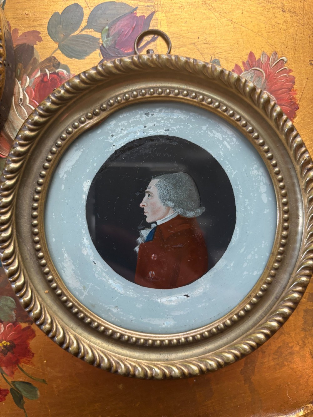 A pair of circular Georgian reverse painted glass miniature profile portraits depicting a lady and gentleman in gilt frames. View III
