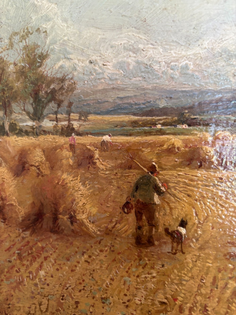 A Victorian landscape oil painting depicting a harvest field with haystacks and a figure, enclosed in an ornate gilded frame with a velvet slip. View V