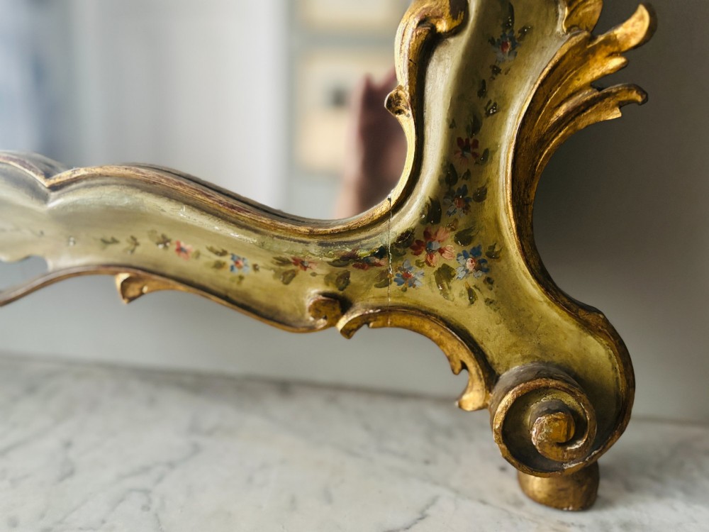 A mid-19th century Italian Venetian wall mirror featuring a carved giltwood frame with scrolling cresting, a sage green polychrome finish, and hand-painted floral detail. View V