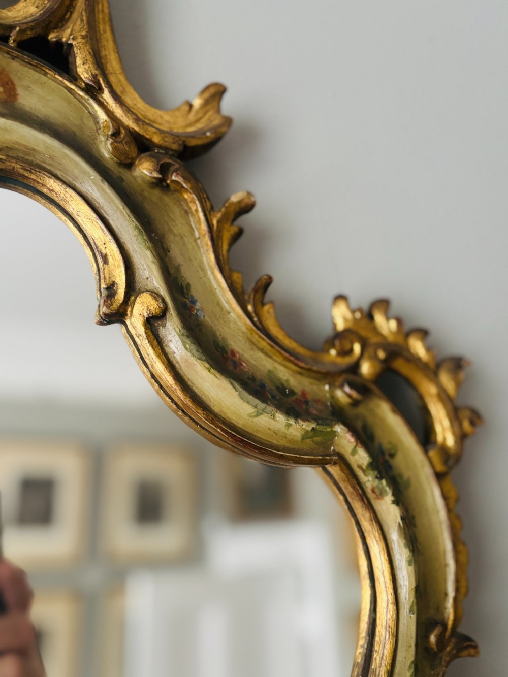 A mid-19th century Italian Venetian wall mirror featuring a carved giltwood frame with scrolling cresting, a sage green polychrome finish, and hand-painted floral detail. View VII