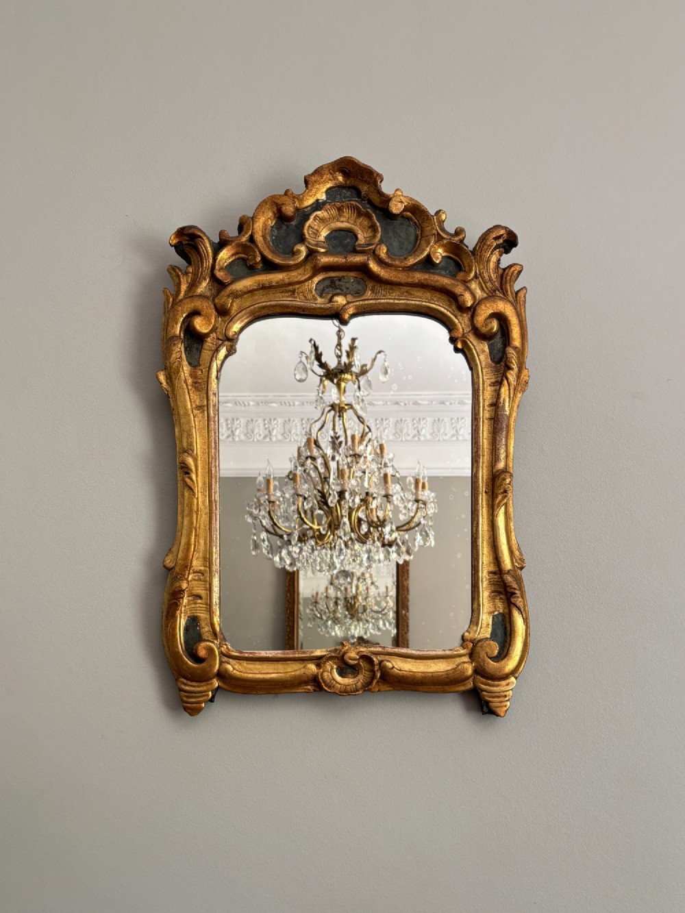 An 18th-century Louis XV giltwood wall mirror featuring an ornate carved shell crest, scrollwork frame, and gold leaf finish. View II