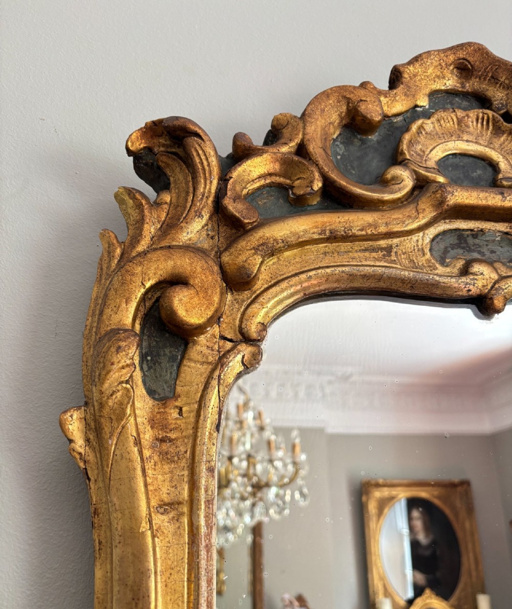 An 18th-century Louis XV giltwood wall mirror featuring an ornate carved shell crest, scrollwork frame, and gold leaf finish. View IV