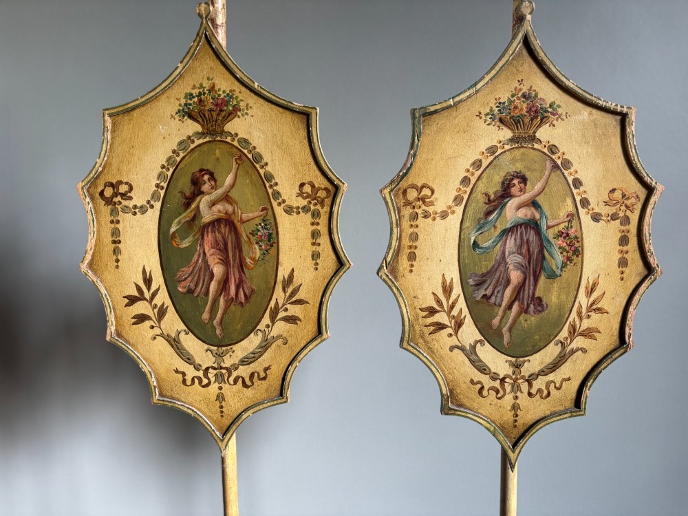 A pair of antique Georgian cream-painted wooden pole screens featuring hand-painted classical figures on shaped panels supported by tripod bases with spade feet. View IX