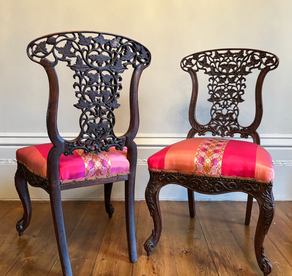 A pair of 19th century Anglo-Indian padauk side chairs with intricately carved openwork foliate backs, cabriole legs, and pink silk upholstery. View VIII