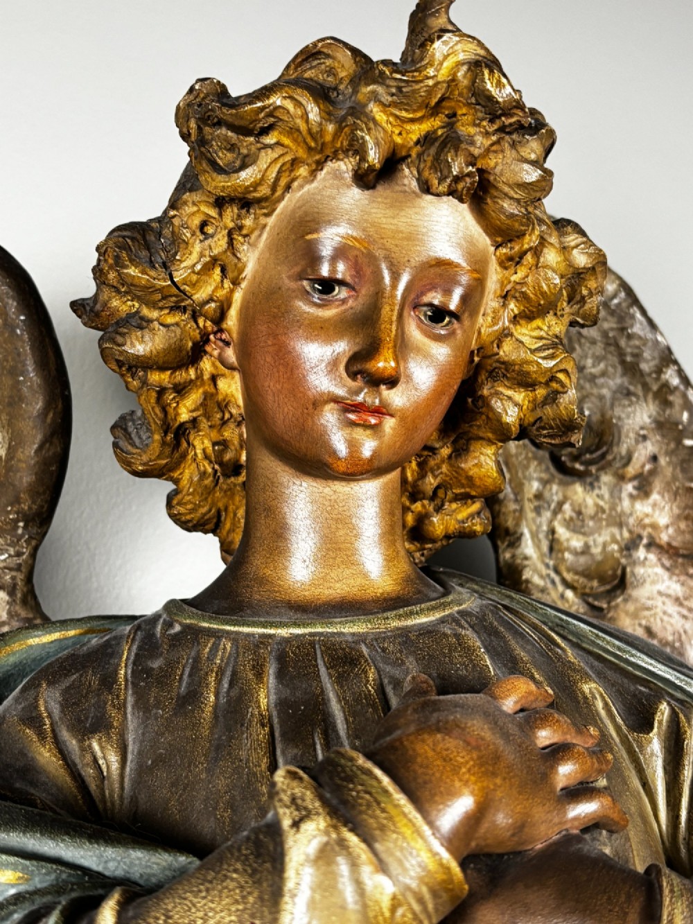 A 19th-century carved Italian wooden angel statue with gold wings, painted drapery in muted blue and ochre tones, and hands resting across its chest. View III