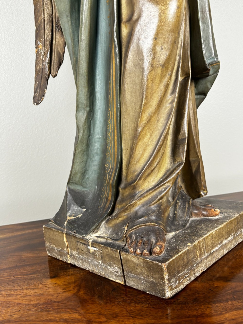A 19th-century carved Italian wooden angel statue with gold wings, painted drapery in muted blue and ochre tones, and hands resting across its chest. View VII
