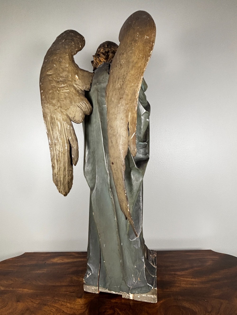 A 19th-century carved Italian wooden angel statue with gold wings, painted drapery in muted blue and ochre tones, and hands resting across its chest. View VIII