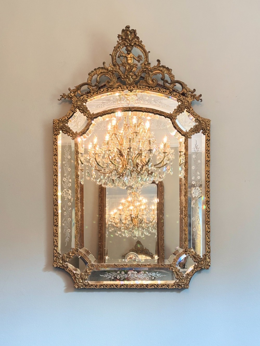 A French Louis XV style wall mirror featuring a gilt bronze frame with a cherub crest, scrollwork details, and etched glass borders. View III