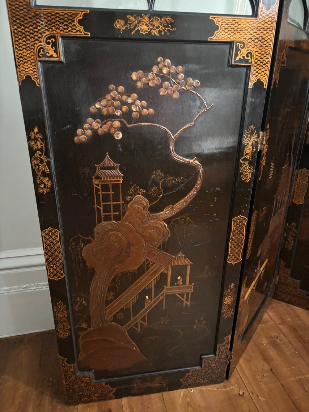 A four-panel black lacquered coromandel screen featuring Chinese Chippendale pagoda crestings, arched glazed tracery windows, and gilt landscape scenes. View VI