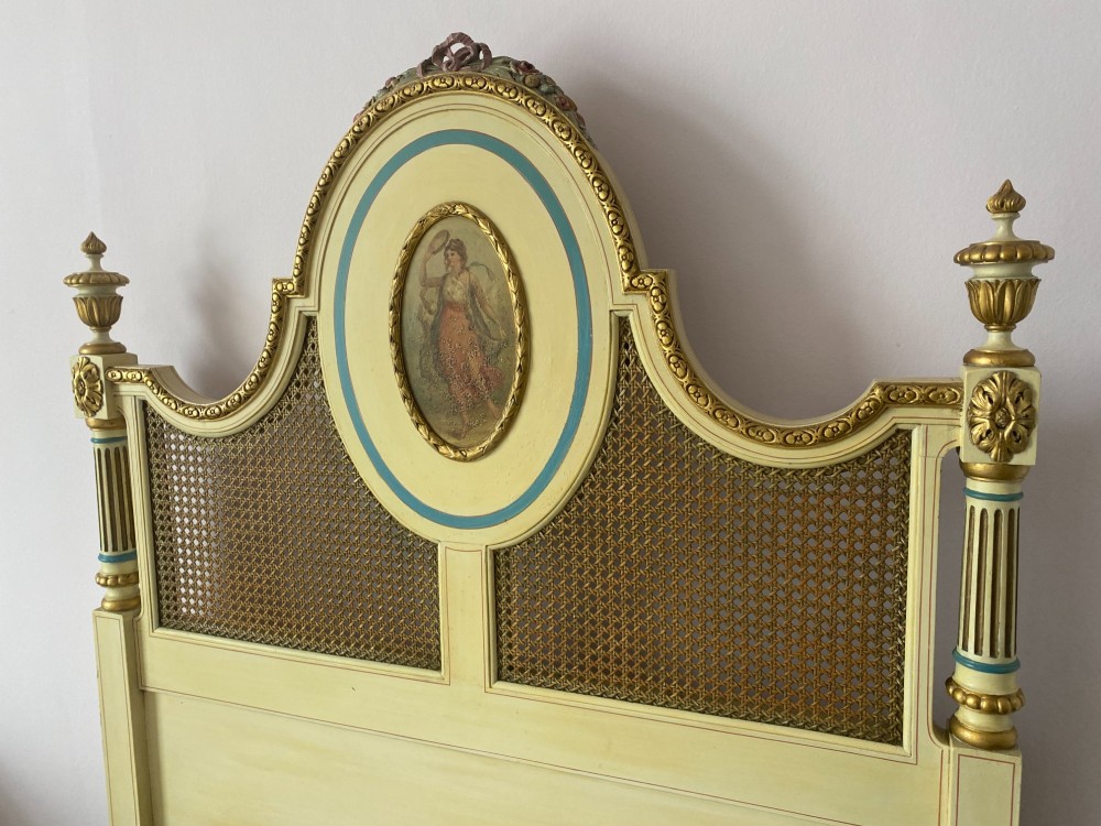 A pair of cream-painted single bedsteads featuring oval hand-painted portrait medallions, woven cane back panels, parcel gilding, and carved paw feet. View IV