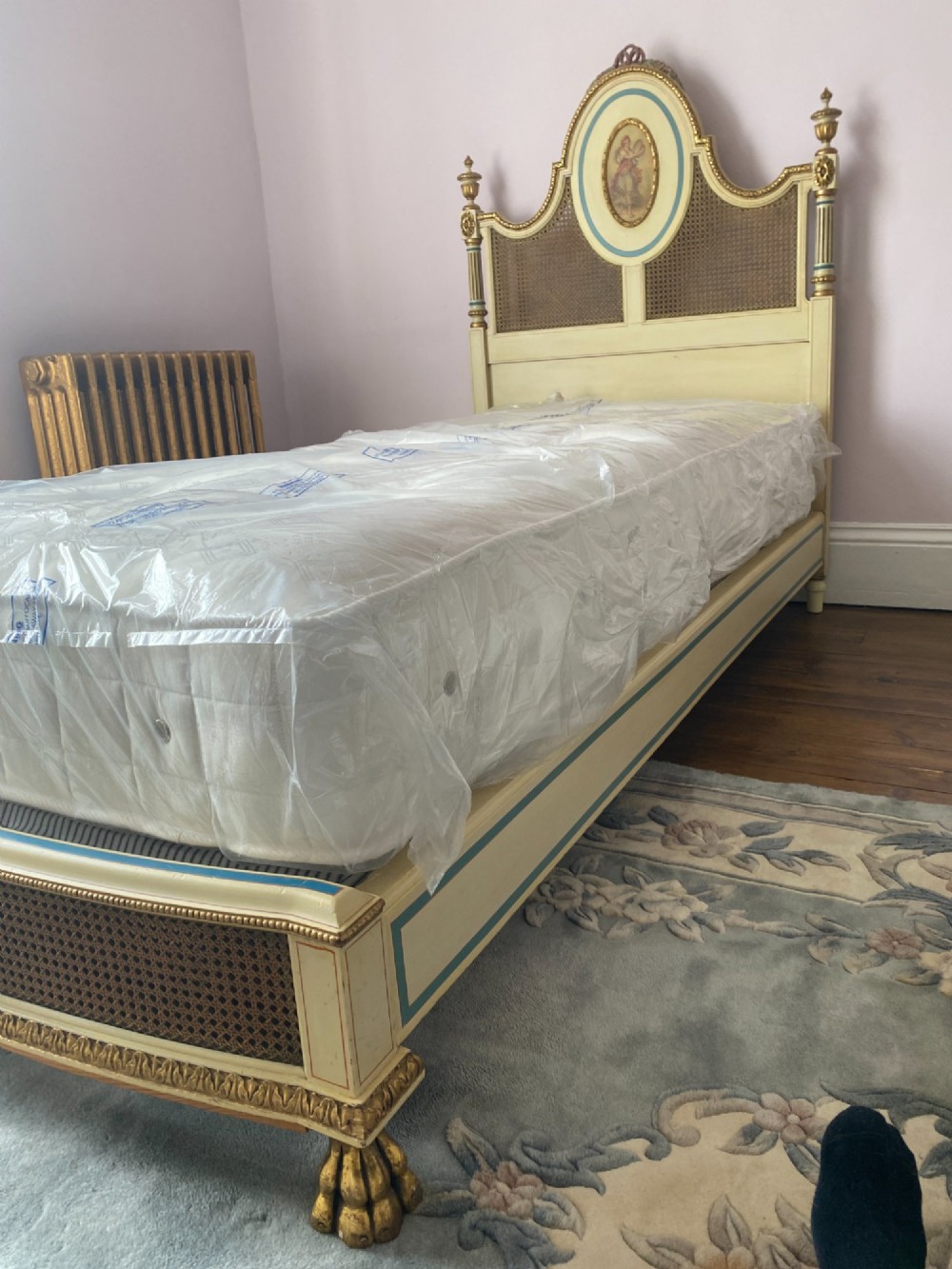 A pair of cream-painted single bedsteads featuring oval hand-painted portrait medallions, woven cane back panels, parcel gilding, and carved paw feet. View VI