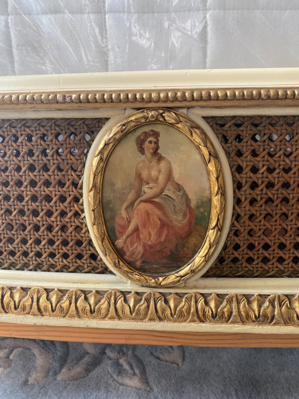 A pair of cream-painted single bedsteads featuring oval hand-painted portrait medallions, woven cane back panels, parcel gilding, and carved paw feet. View IX