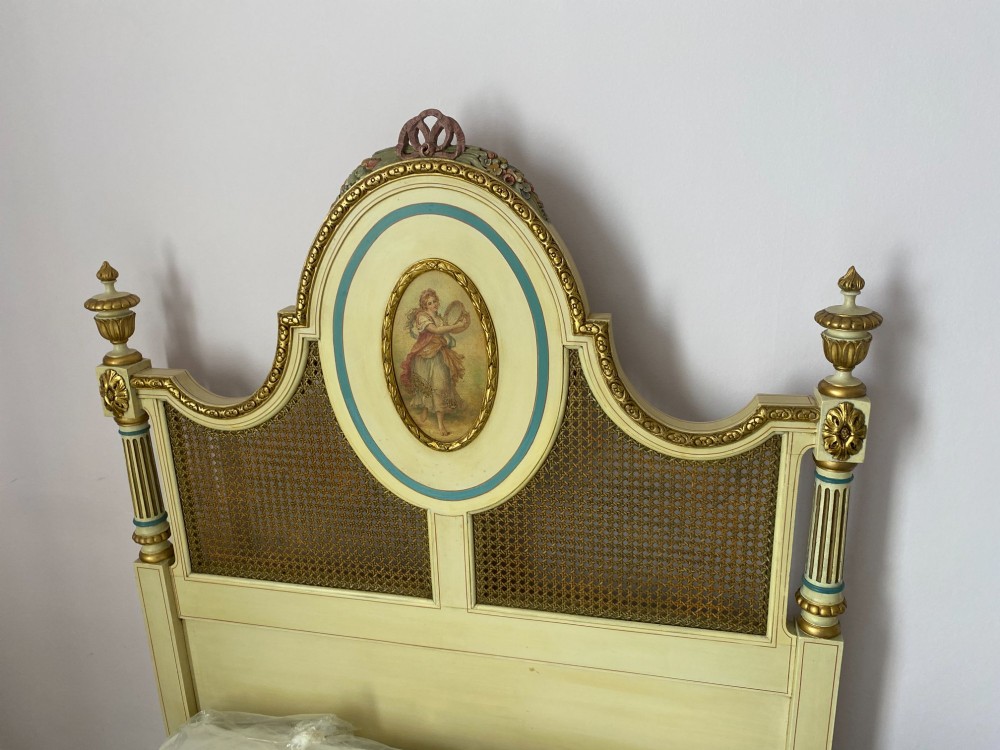 A pair of cream-painted single bedsteads featuring oval hand-painted portrait medallions, woven cane back panels, parcel gilding, and carved paw feet. View XIV