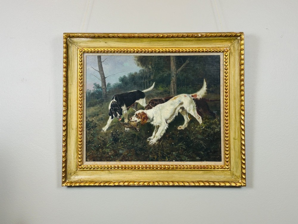 A framed oil painting on canvas depicting hunting dogs retrieving a game bird in a woodland clearing. View II