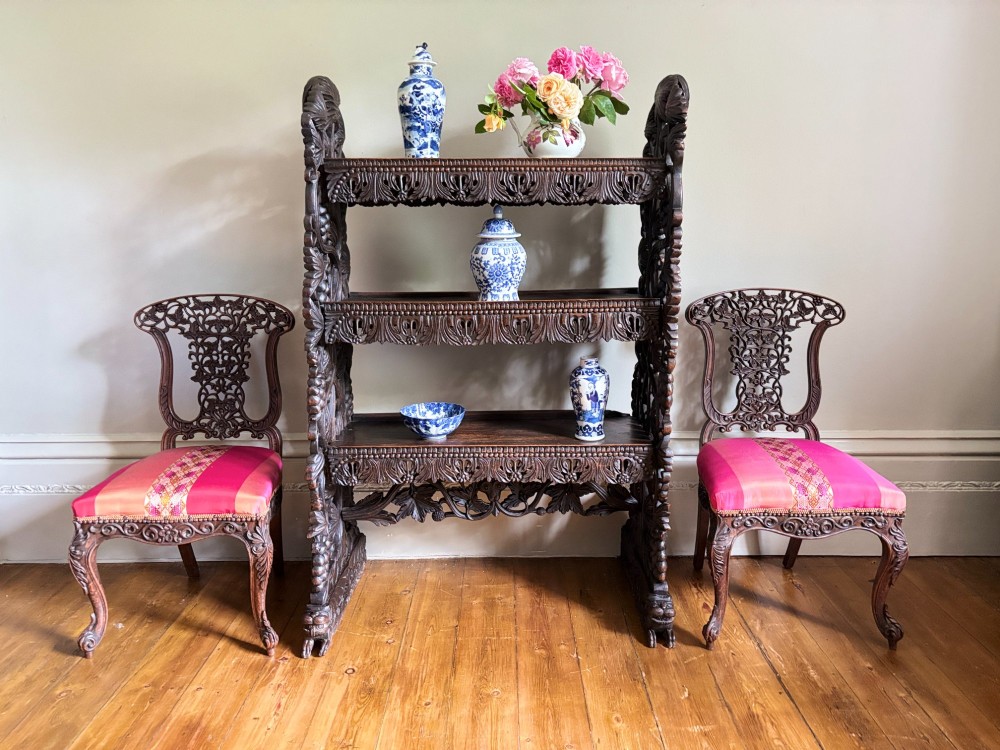 A mid-19th-century Anglo-Indian dark padauk wood open shelving unit with three tiers, intricate foliate carving, pierced aprons, and carved feet. View X