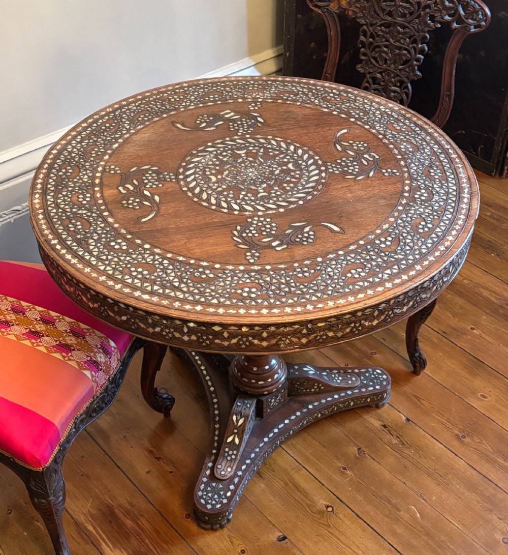 A 19th-century circular Anglo-Indian pedestal table made of dark hardwood with geometric mother-of-pearl inlay across the top, apron, turned column, and tripod base. View IV