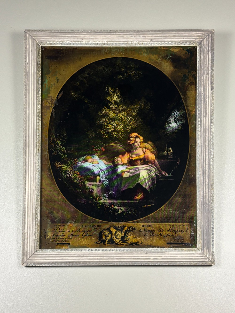 A rectangular framed Georgian reverse glass print depicting a classical maternal scene titled La Bonne Mere set within an oval border.