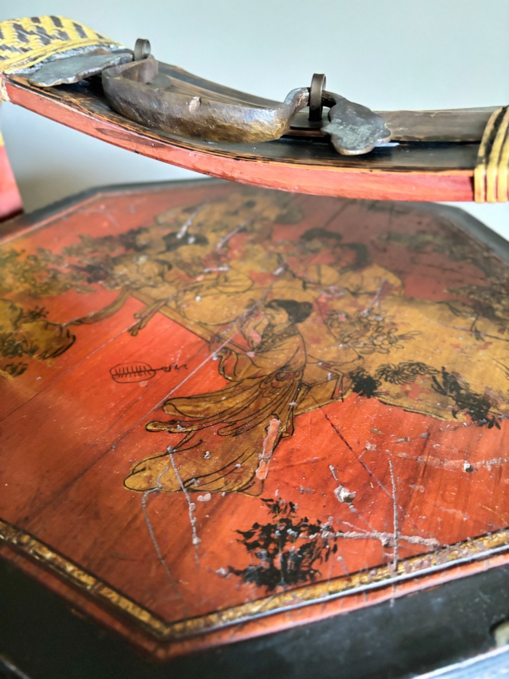 An octagonal three-tiered Chinese lacquer dowry basket decorated with hand-painted narrative panels and a high arched handle. View VI