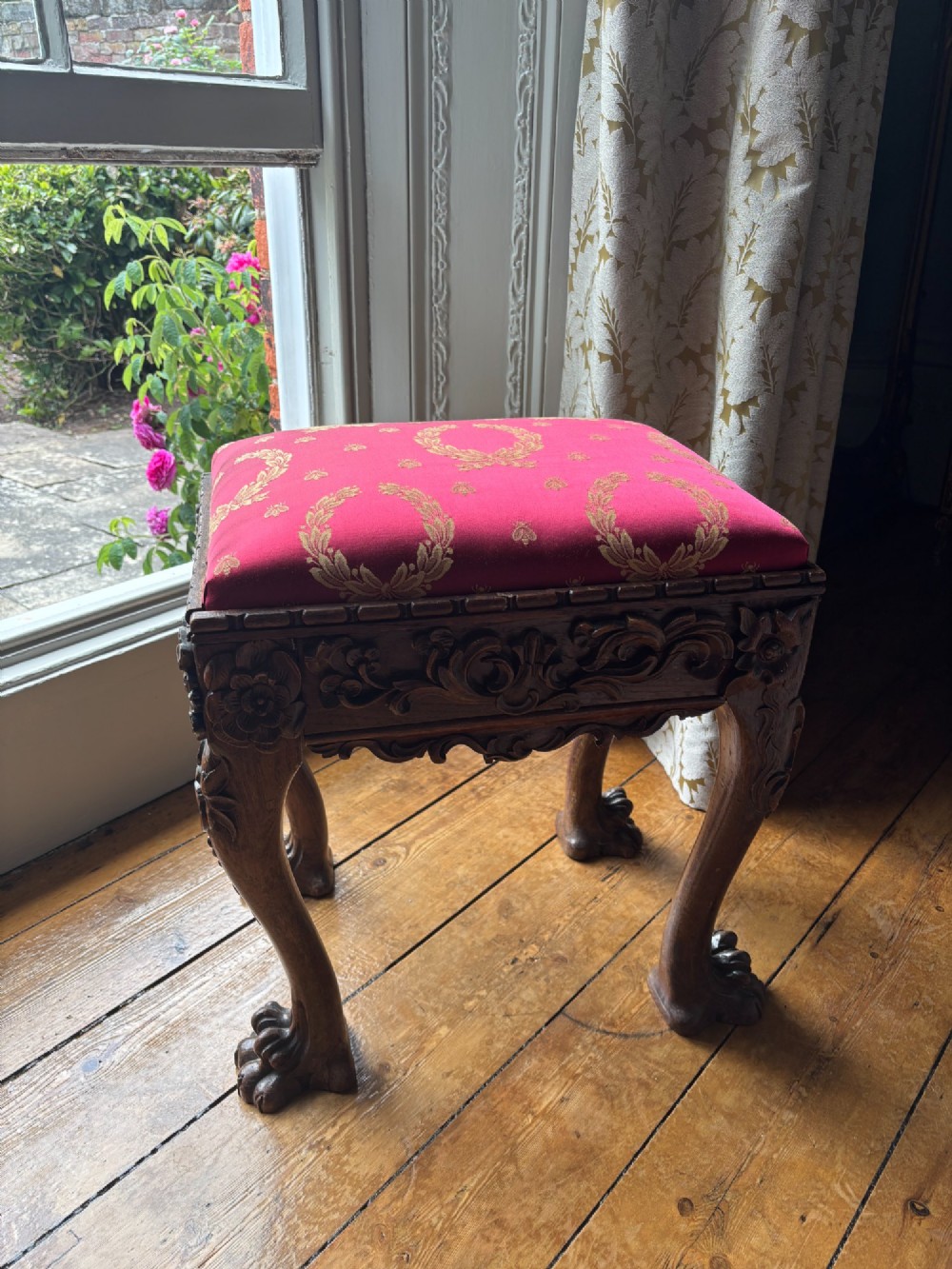 A Victorian Chippendale style carved timber stool featuring cabriole legs with claw feet and a padded red top upholstered in fabric with gold embroidery. View II