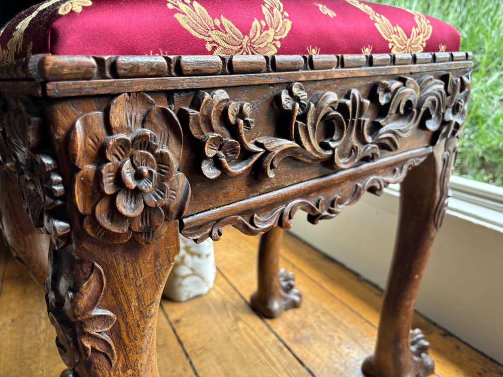 A Victorian Chippendale style carved timber stool featuring cabriole legs with claw feet and a padded red top upholstered in fabric with gold embroidery. View VII