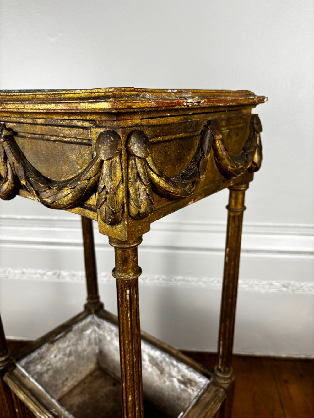 A two-tiered French Empire giltwood jardinere stand featuring carved festoons, fluted supports, and a lower caned trough with a removable metal liner. View V
