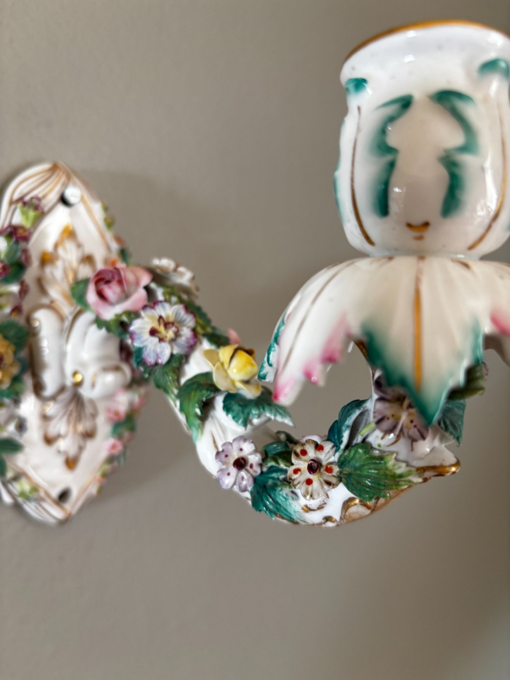 A white porcelain single candle wall sconce with hand-painted applied floral decorations, green foliage, and gilded Rococo scrollwork. View IV