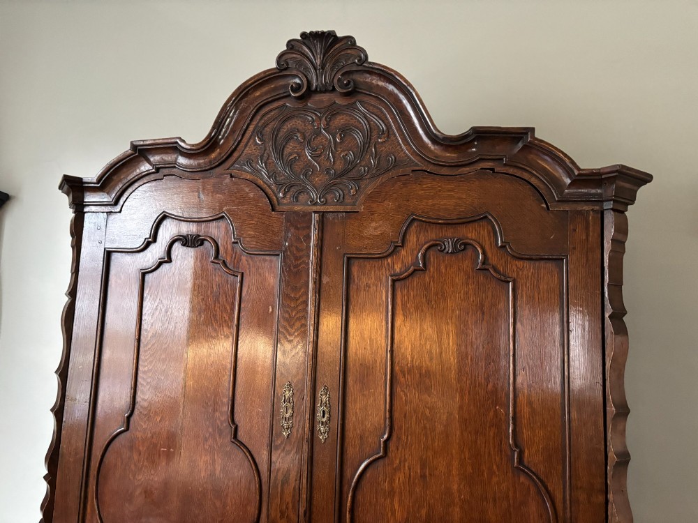 An 18th-century Dutch oak linen press featuring an arched pediment, two carved panel doors, three lower drawers, and brass handles. View IV