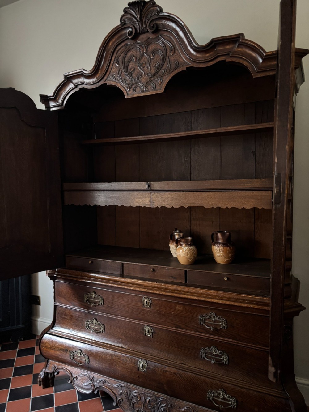 An 18th-century Dutch oak linen press featuring an arched pediment, two carved panel doors, three lower drawers, and brass handles. View VIII