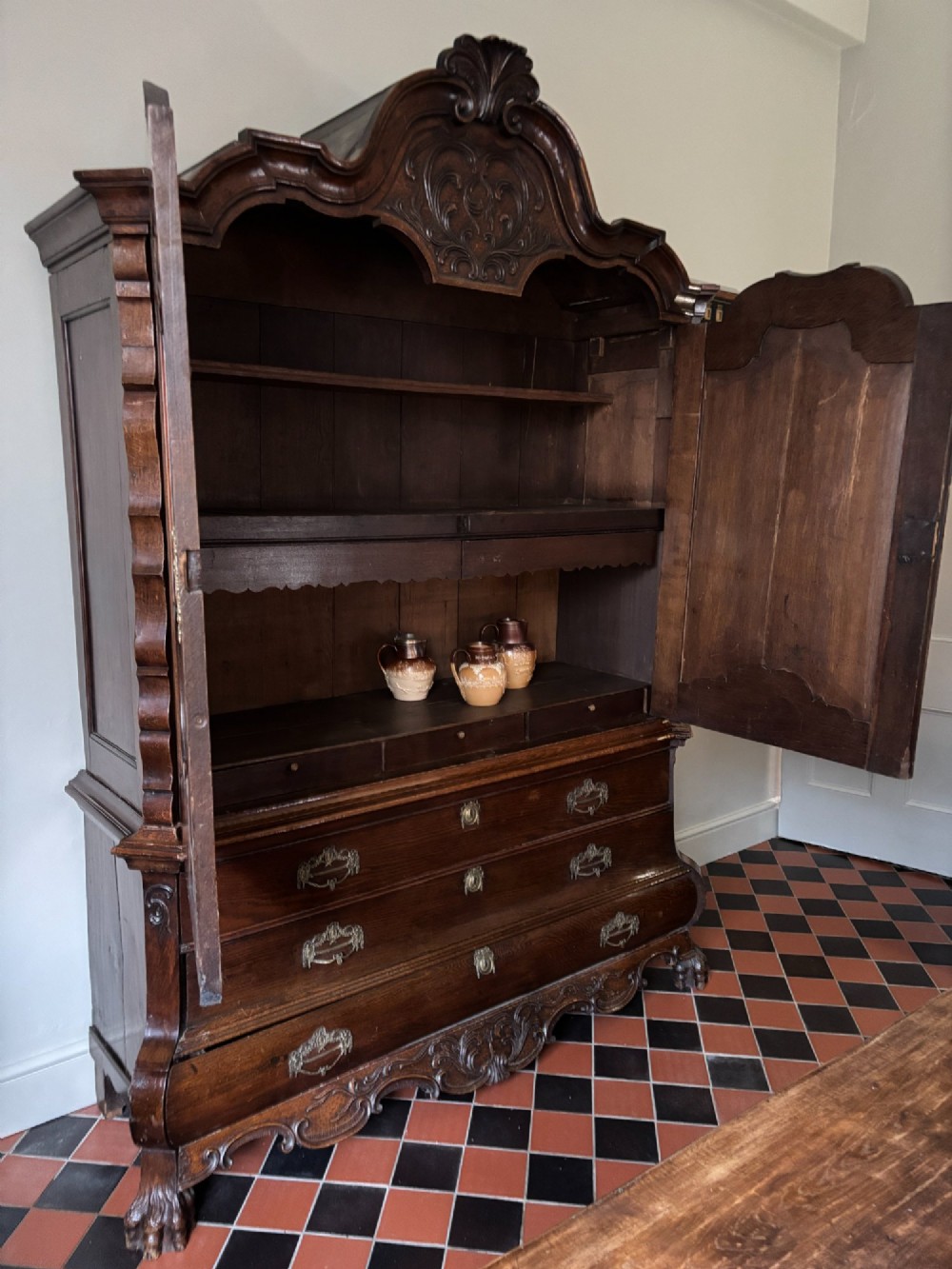 An 18th-century Dutch oak linen press featuring an arched pediment, two carved panel doors, three lower drawers, and brass handles. View IX