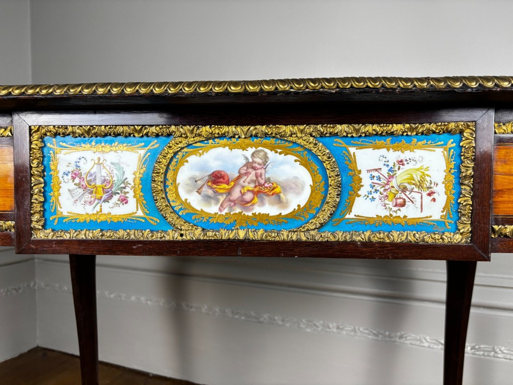 A Louis XV style rosewood writing table featuring cabriole legs, gilt bronze ormolu mounts, and blue porcelain plaques set into the frieze. View VII