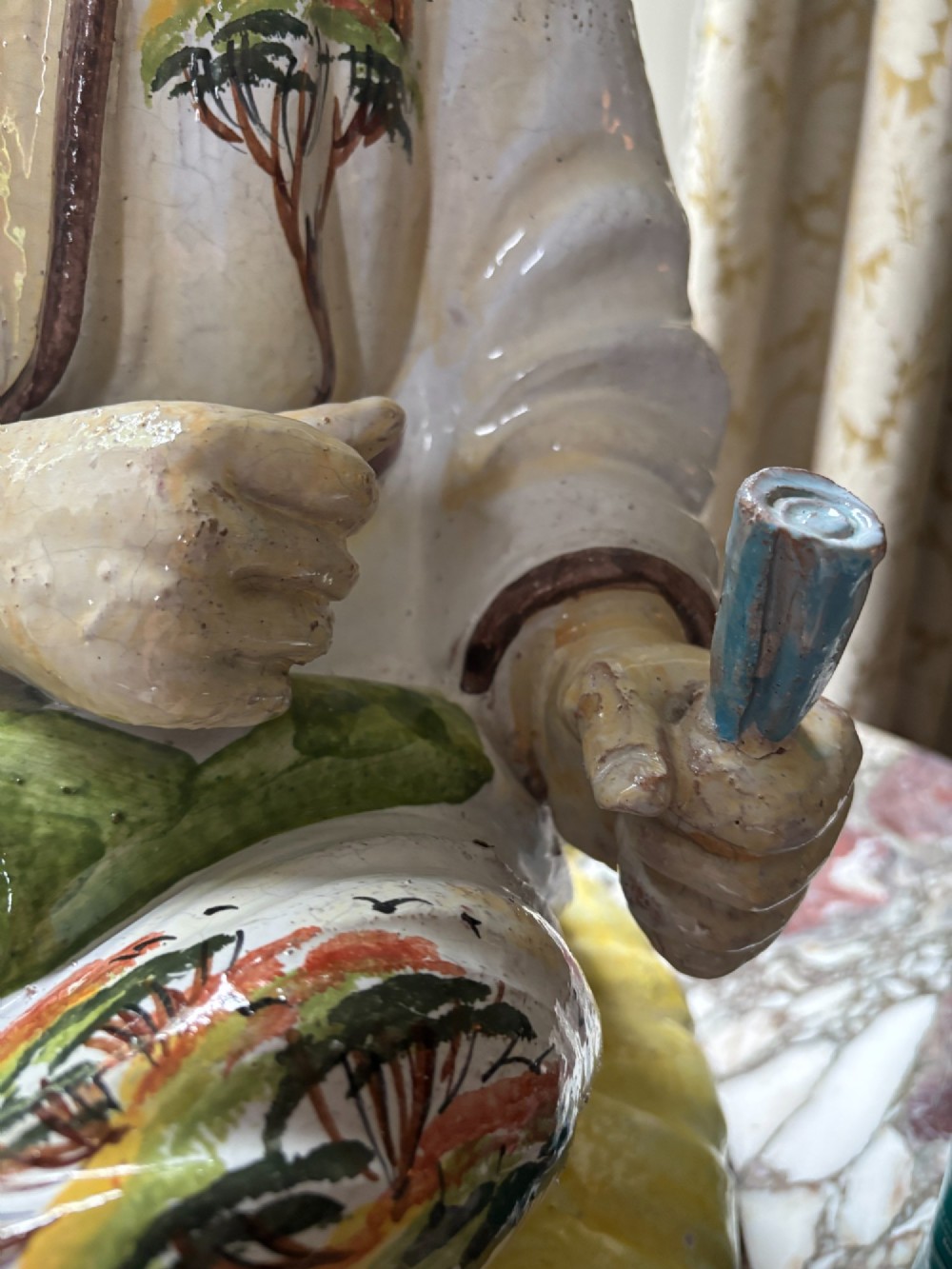 A polychrome glazed Italian ceramic figure of a seated Chinese scholar dressed in robes on a yellow cushion. View V