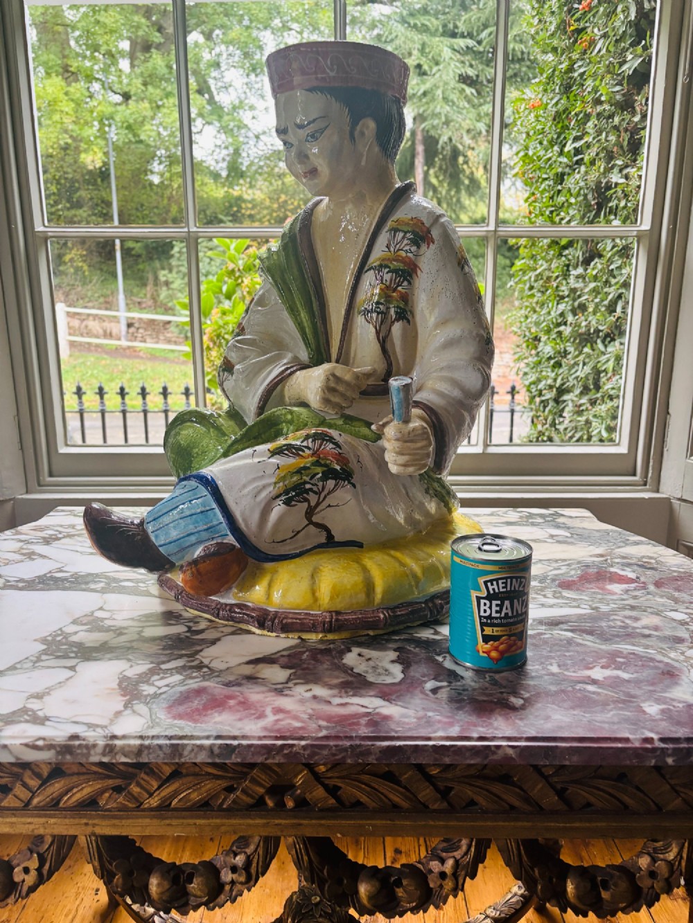 A polychrome glazed Italian ceramic figure of a seated Chinese scholar dressed in robes on a yellow cushion. View XI