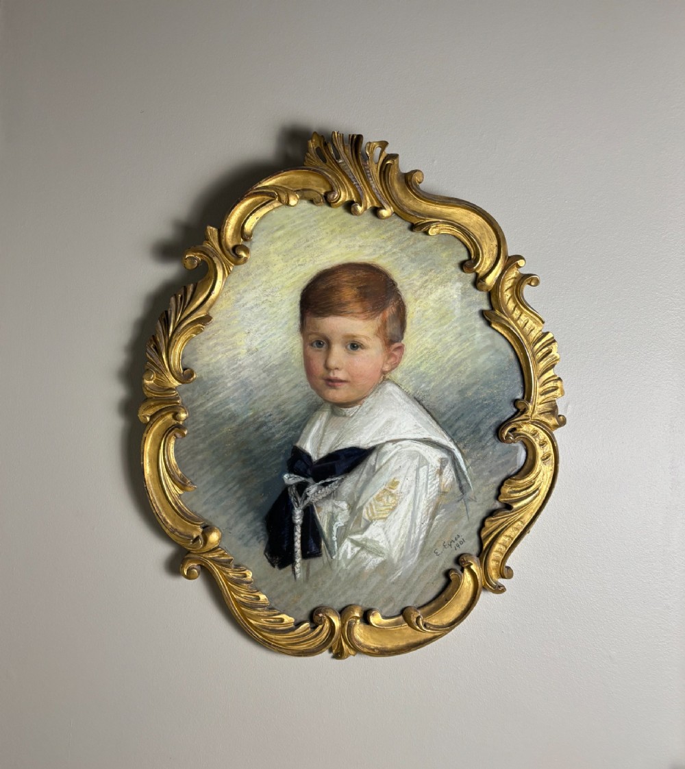 An oval Edwardian portrait of a young boy wearing a white sailor suit, set within a gilt scrollwork frame. View II