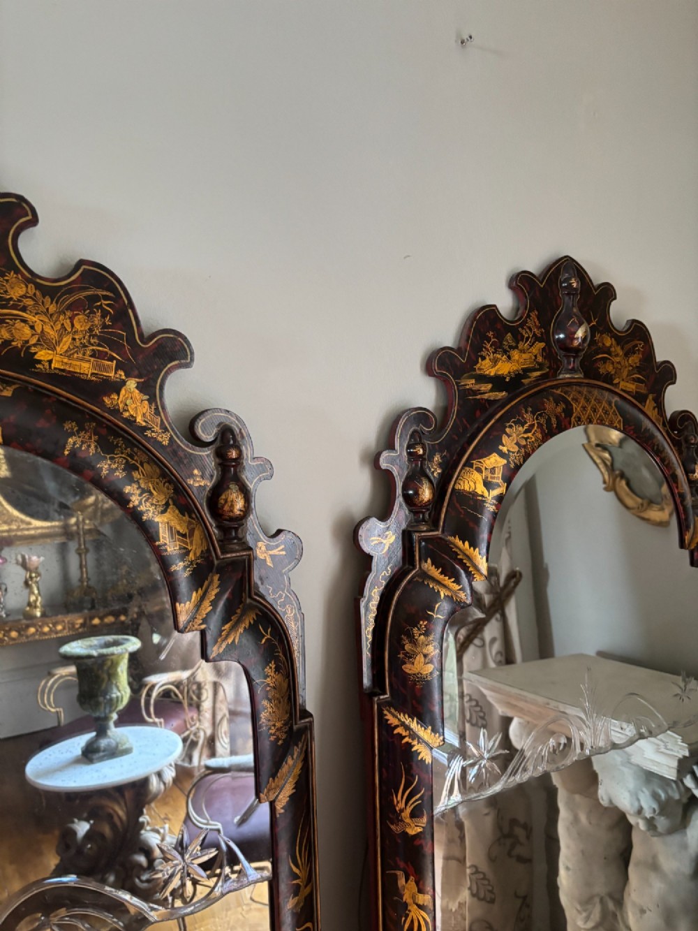A pair of tall arched Queen Anne style wall mirrors featuring black japanned frames decorated with gilded chinoiserie motifs and cut glass crests. View XV