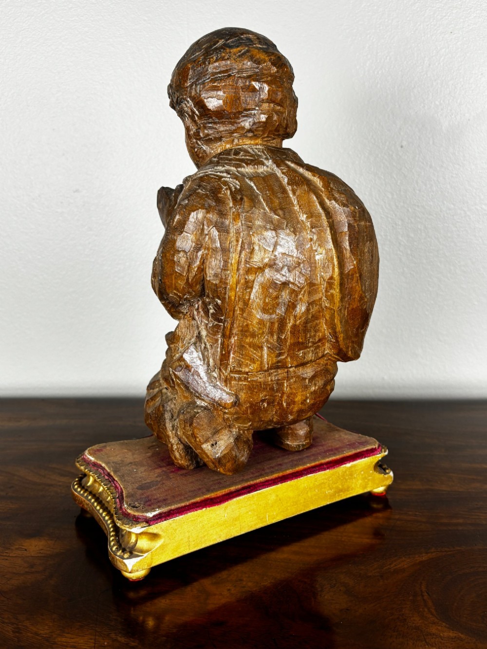 A late 18th-century carved limewood figure of a kneeling youth with hands folded in prayer, mounted on a velvet and gilded wooden base. View V