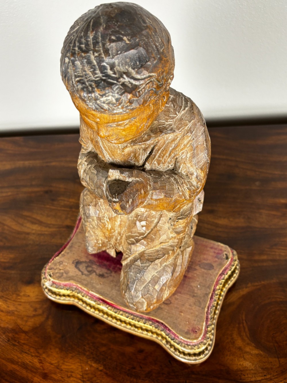 A late 18th-century carved limewood figure of a kneeling youth with hands folded in prayer, mounted on a velvet and gilded wooden base. View VI